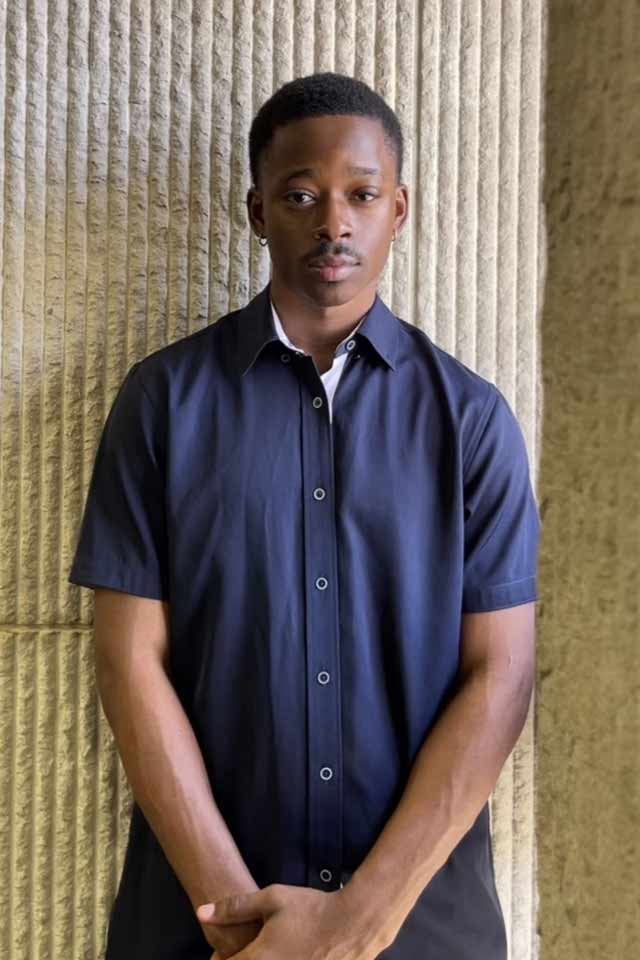 A confidant young man standing outside next to a wall